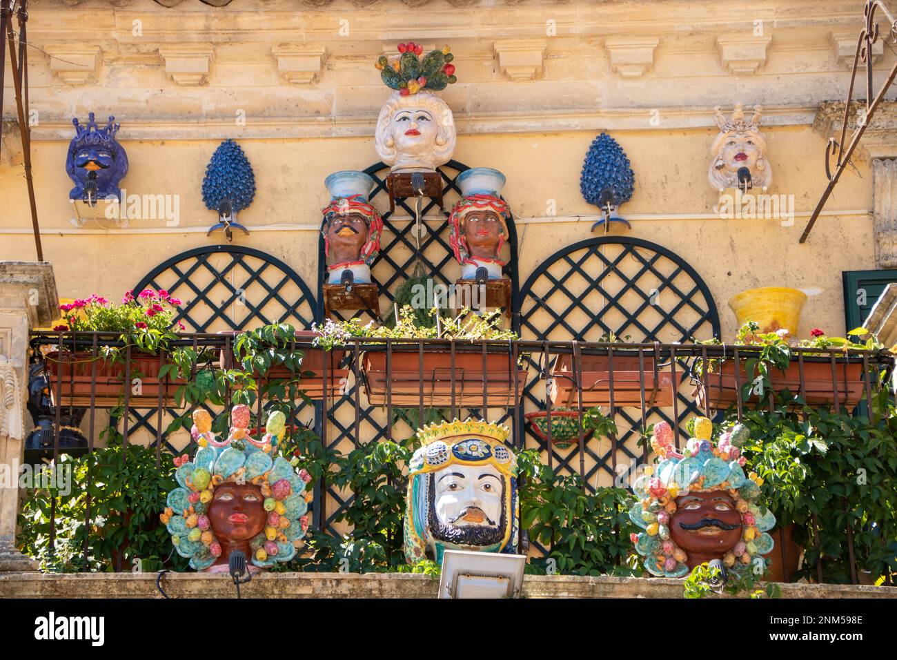 A Palazzolo Acreide , Italia , il 03 - 08 - 2022 - Ceramica tradizionale teste e coni di pino su un balcone barocco, Sicilia, Italia Foto Stock