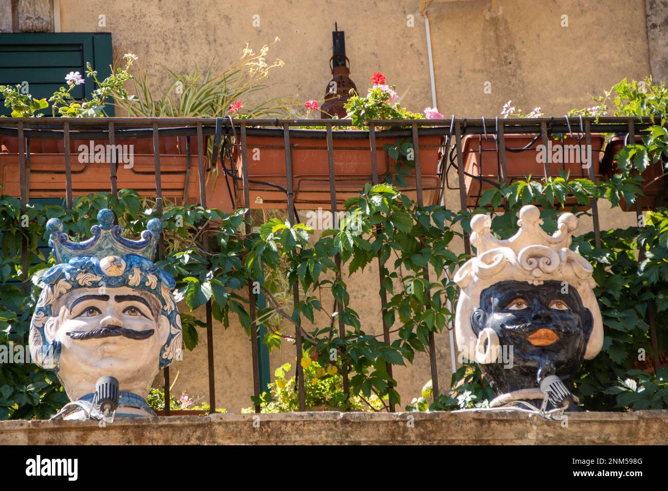 A Palazzolo Acreide , Italia , il 03 - 08 - 2022 - Ceramica tradizionale teste e coni di pino su un balcone barocco, Sicilia, Italia Foto Stock