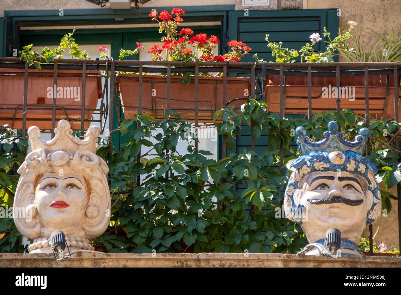 A Palazzolo Acreide , Italia , il 03 - 08 - 2022 - Ceramica tradizionale teste e coni di pino su un balcone barocco, Sicilia, Italia Foto Stock
