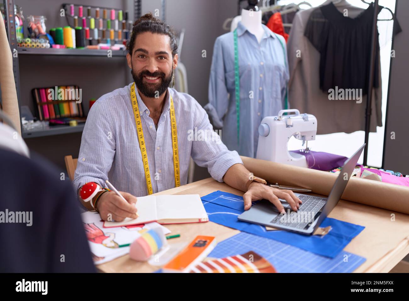 Giovane uomo ispanico su misura utilizzando la scrittura touchpad su  notebook presso atelier Foto stock - Alamy