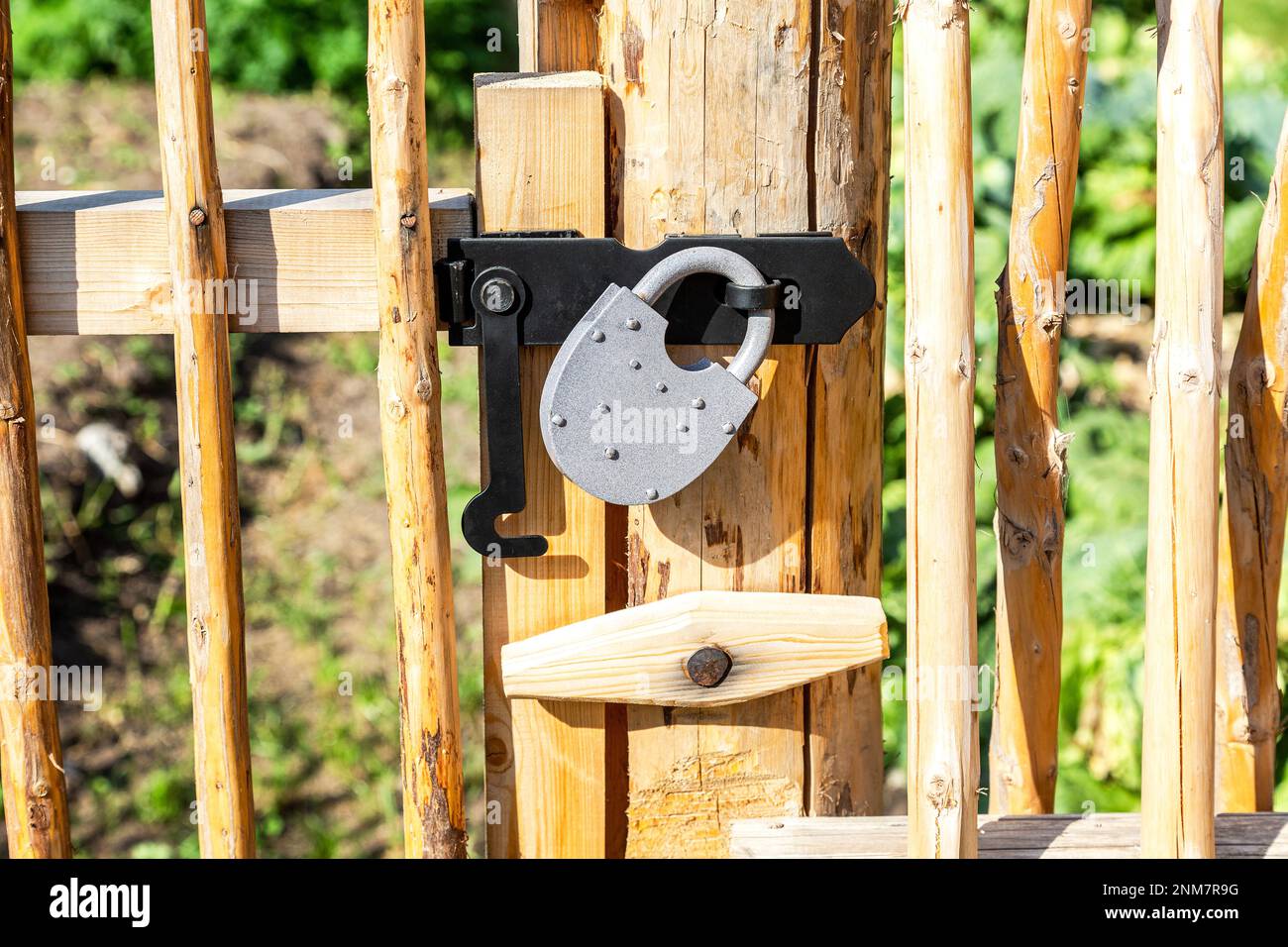 Nuovo lucchetto di metallo su una recinzione di legno giallo brillante nel villaggio Foto Stock