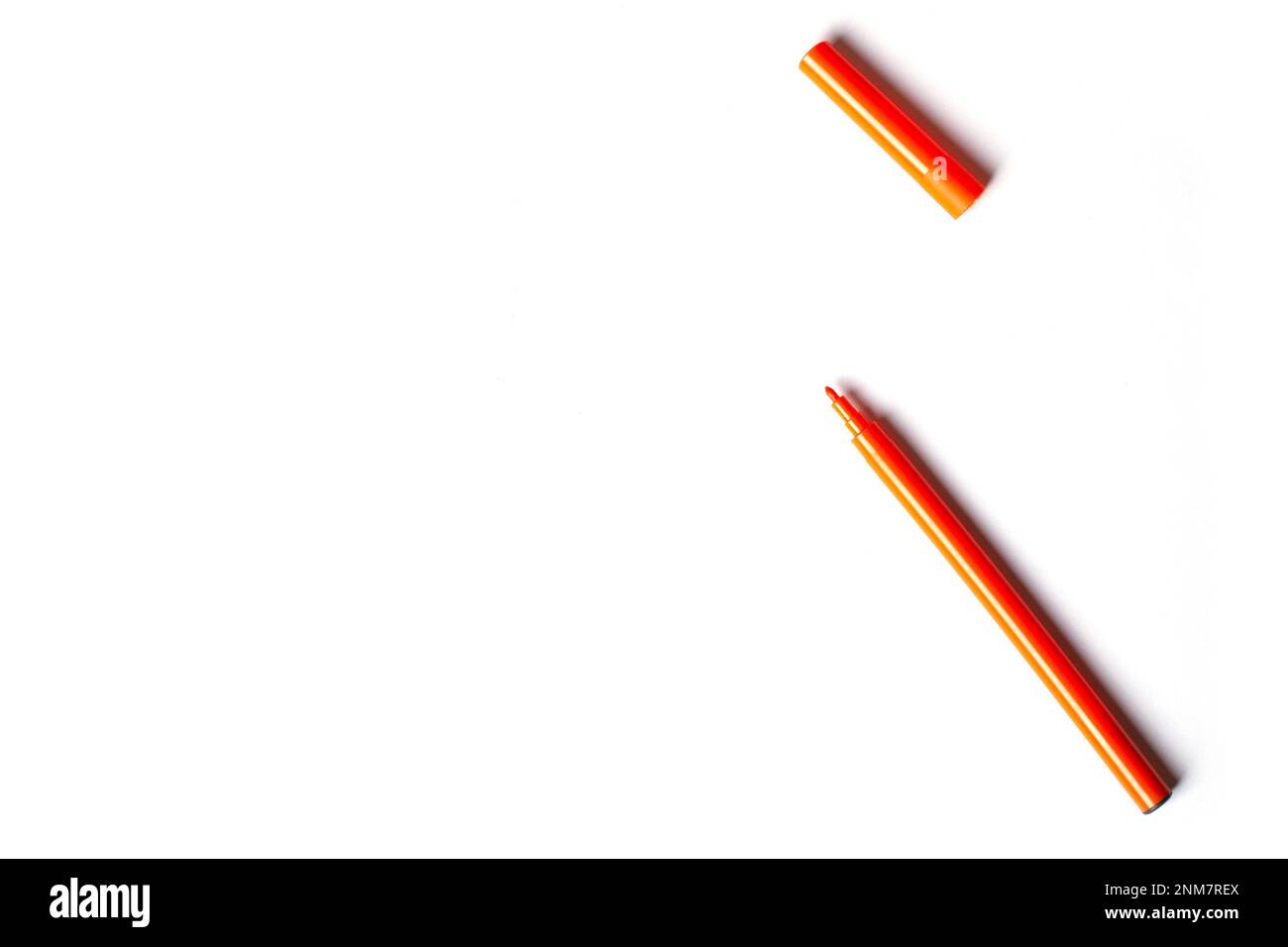 Una penna arancione con punta in feltro e cappuccio si trova su uno sfondo bianco. spazio vuoto per la scrittura Foto Stock