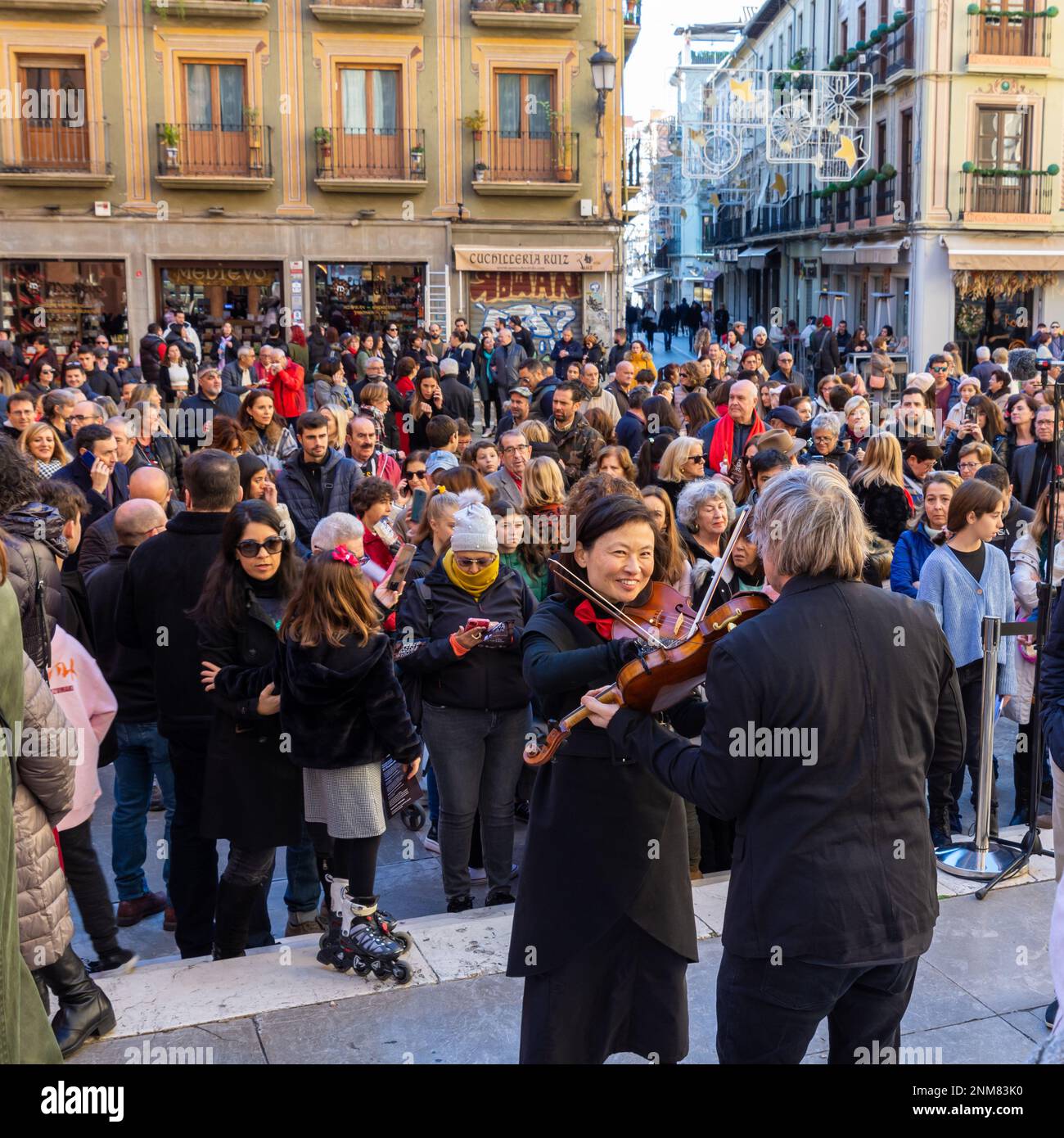 Granada, Spagna; 18 dicembre 2022: Alcuni musicisti e il direttore della Granada Symphony Orchestra suonano un carol di Natale per strada Foto Stock