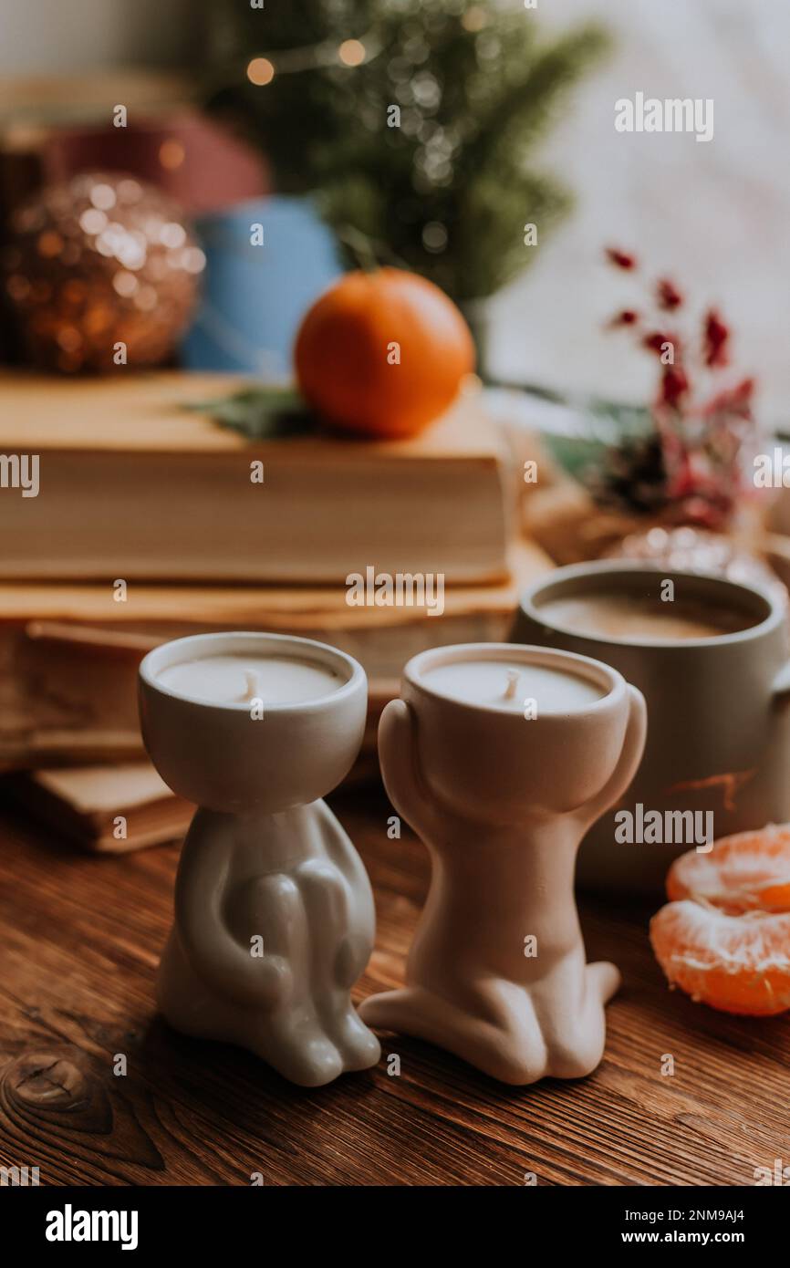 Candele profumate fatte a mano, caffè, libri e tangerini per il nuovo anno. Atmosfera accogliente di Natale a casa Foto Stock