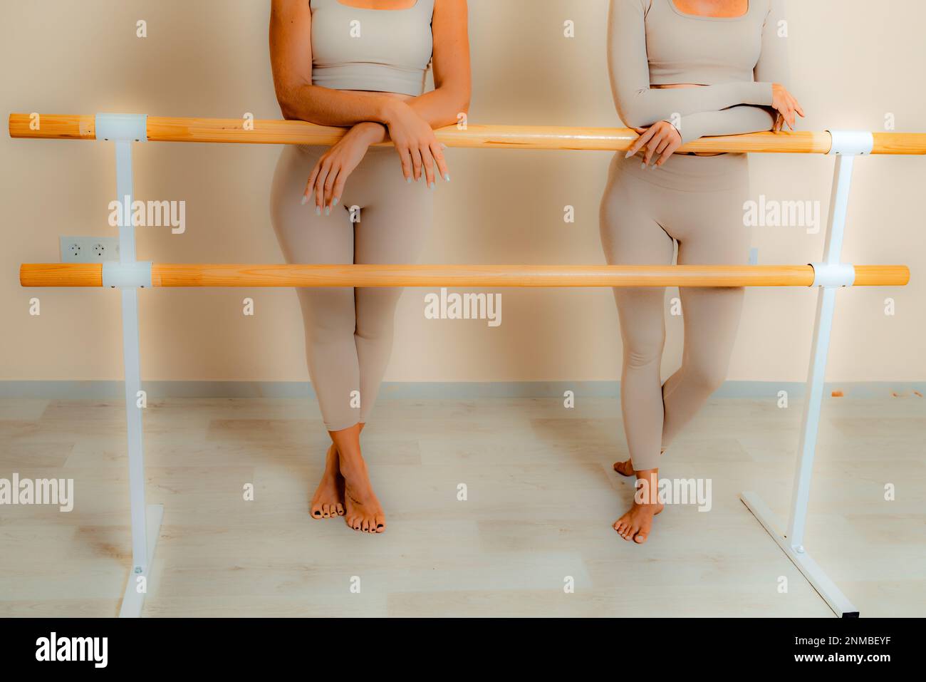 Vicino alla barra, nella sala coreografica, due donne in una parte superiore beige e leggings sono impegnati. Foto Stock