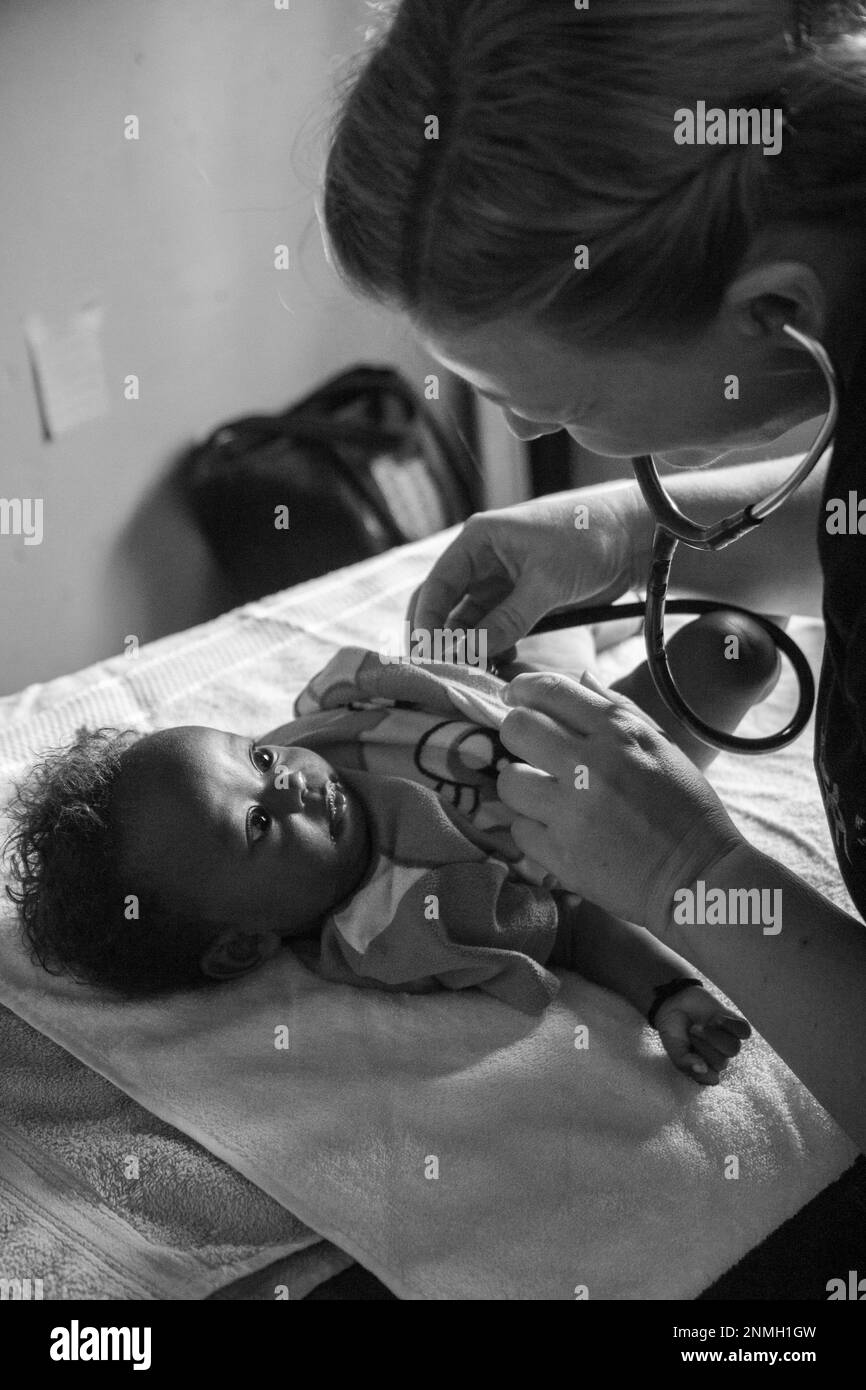 Un medico bianco che esamina un bambino nero con uno stetoscopio. Foto Stock