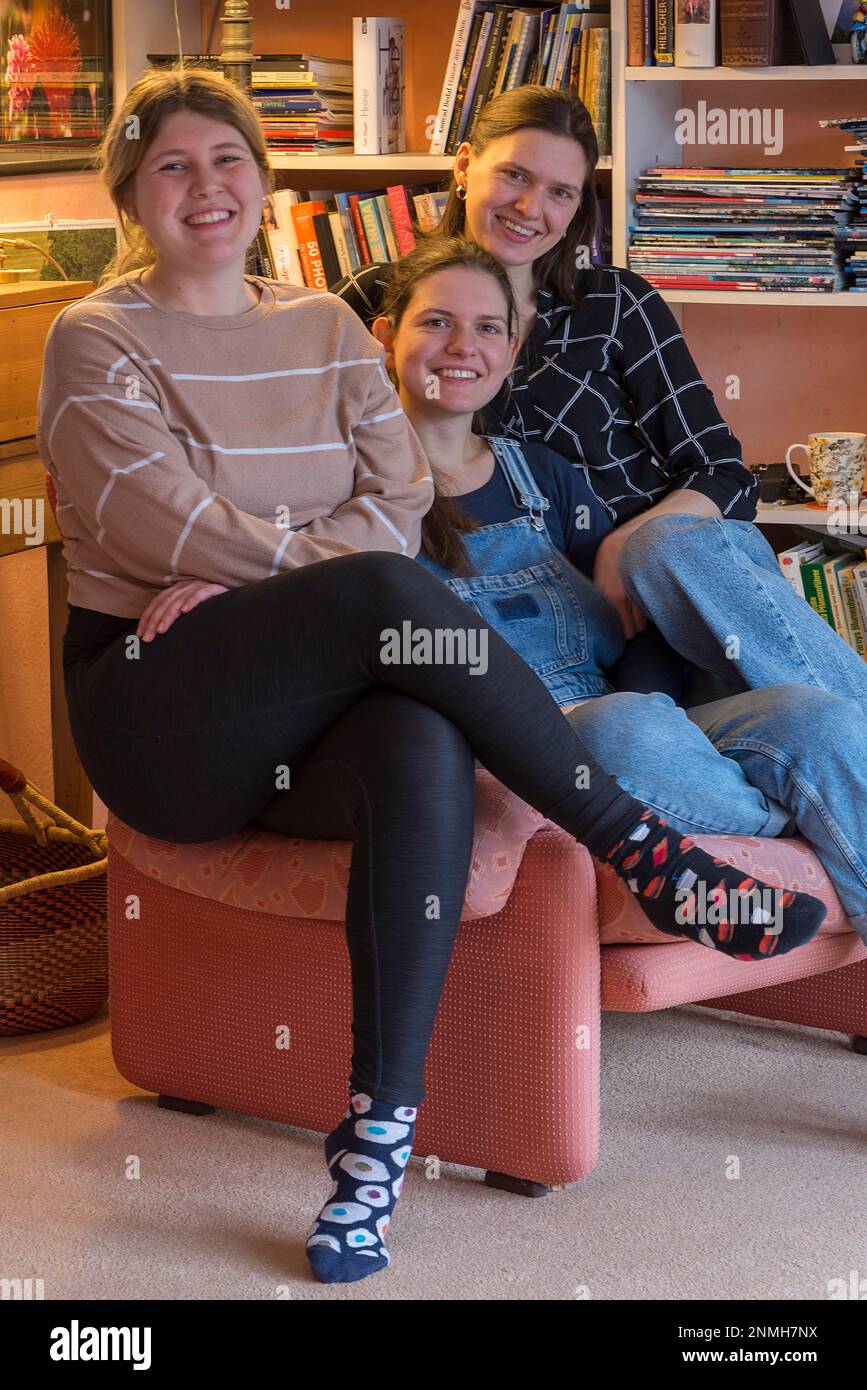 Tre giovane donna seduta su una poltrona., Baviera, Germania Foto Stock