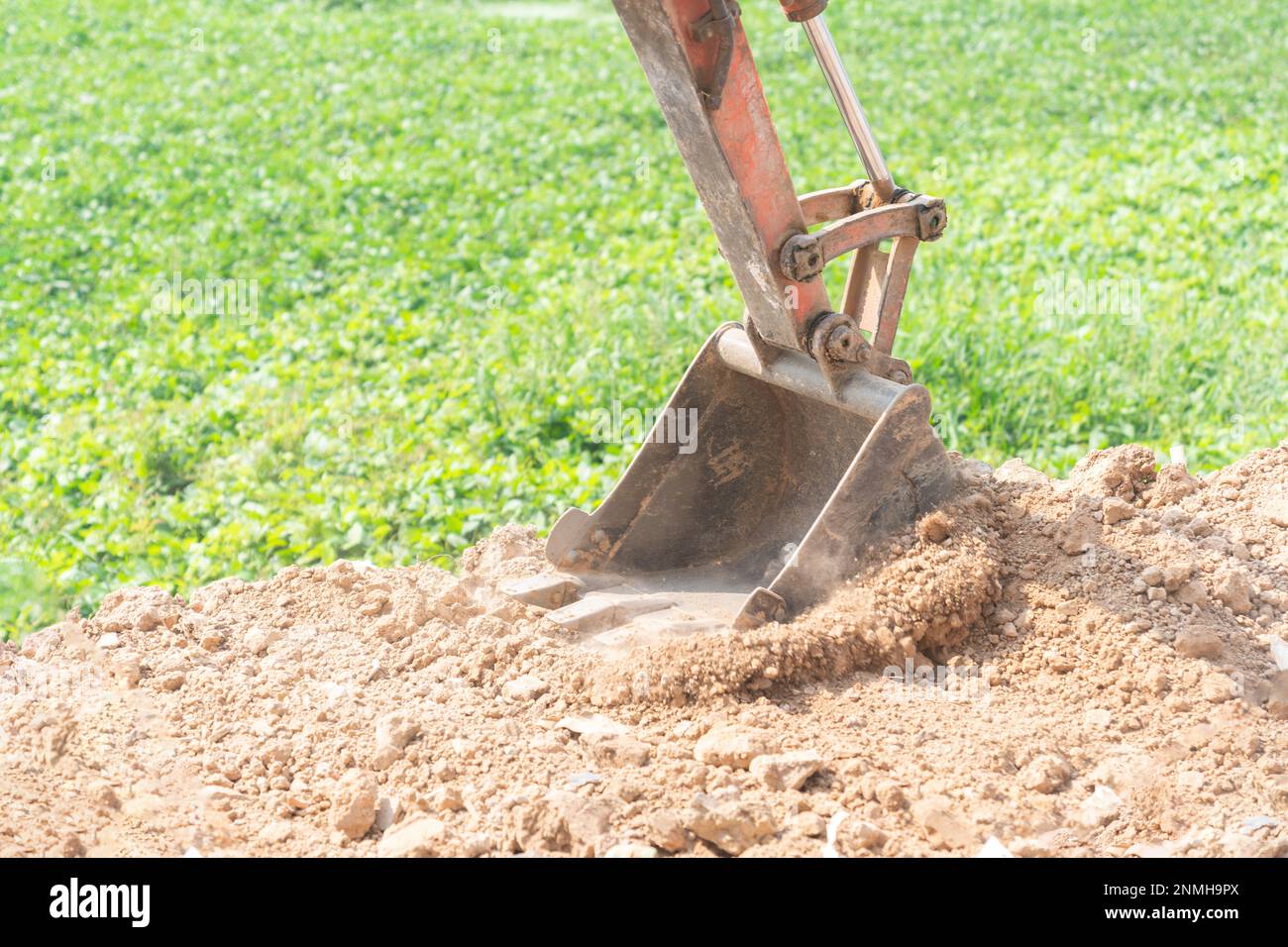 Primo piano della benna mini-scavatrice che scava il terreno in un cantiere edile. Foto Stock