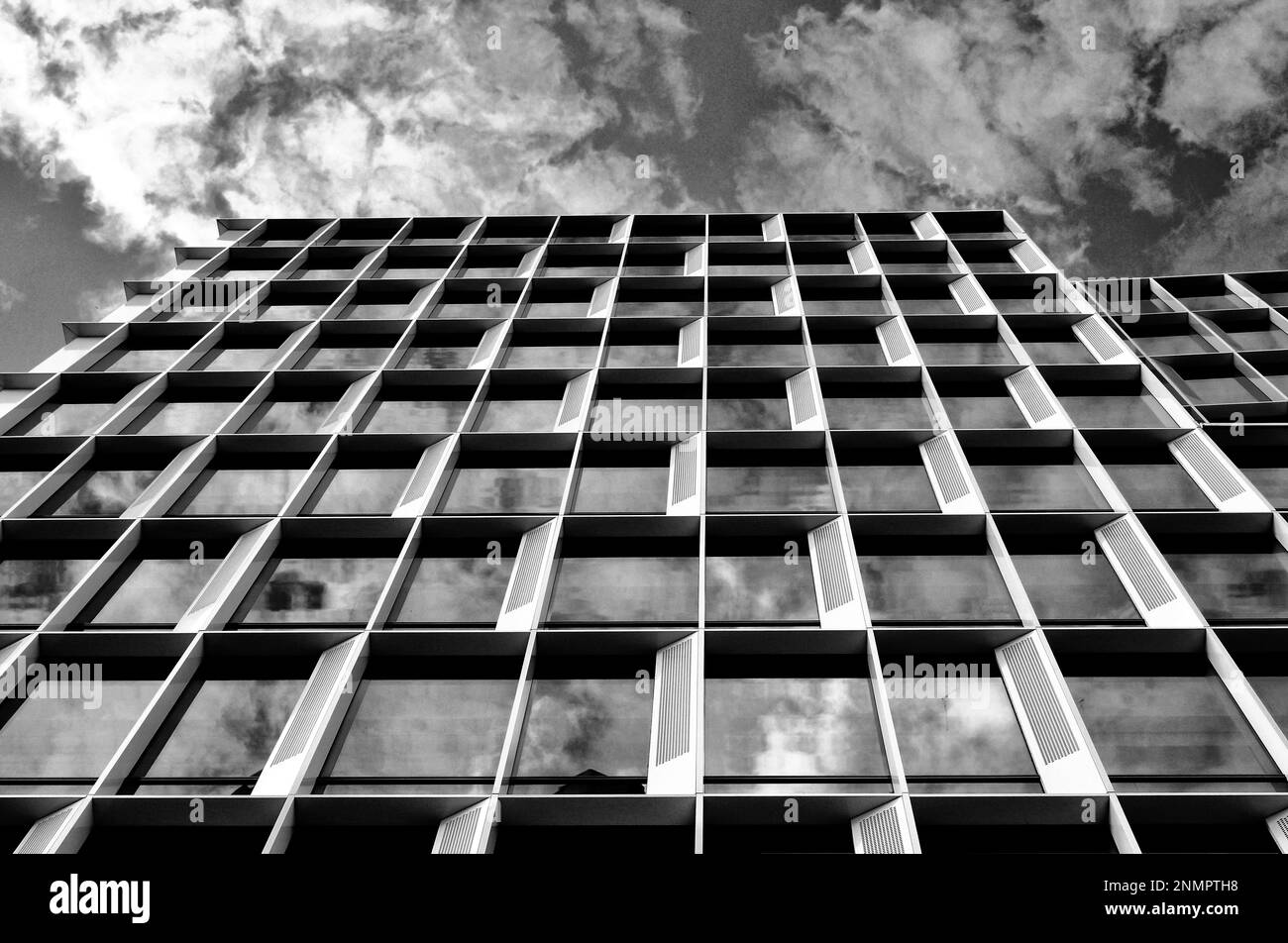 facciata torre di uffici in vetro e alluminio. riduzione della prospettiva. vista ad angolo basso. architettura e design moderni. cielo dinamico con nuvole bianche Foto Stock