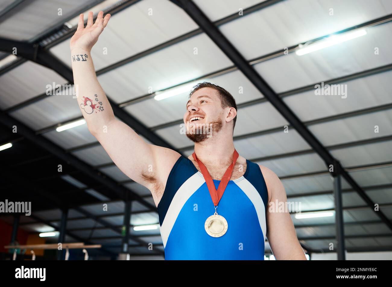 Uomo, medaglia celebrazione e vincendo sorriso con onde, sport e mano in aria in concorrenza con orgoglio. Atleta campione, felice e vincitore con oro Foto Stock