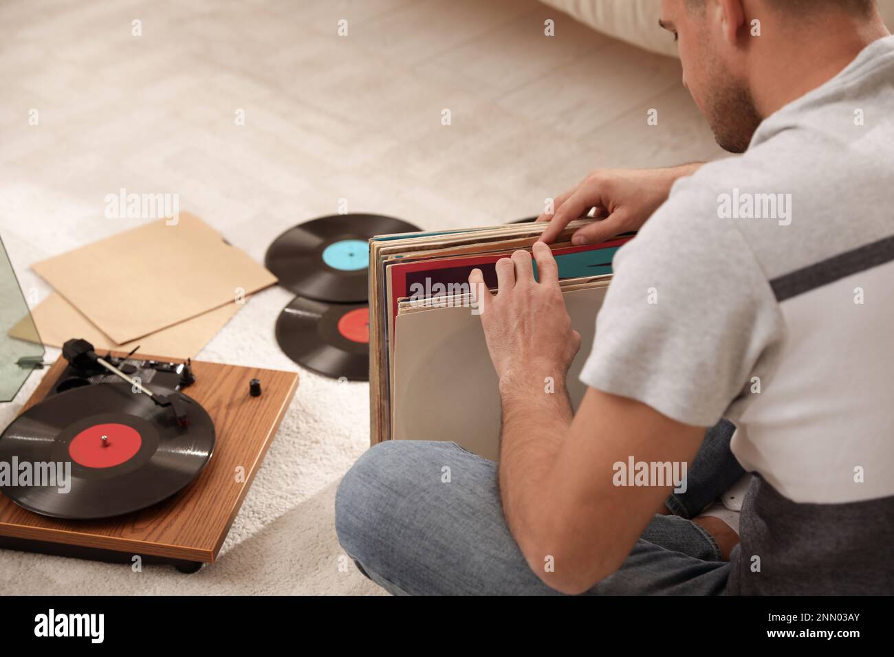 Uomo con collezione di dischi in vinile vicino al giradischi a casa Foto Stock