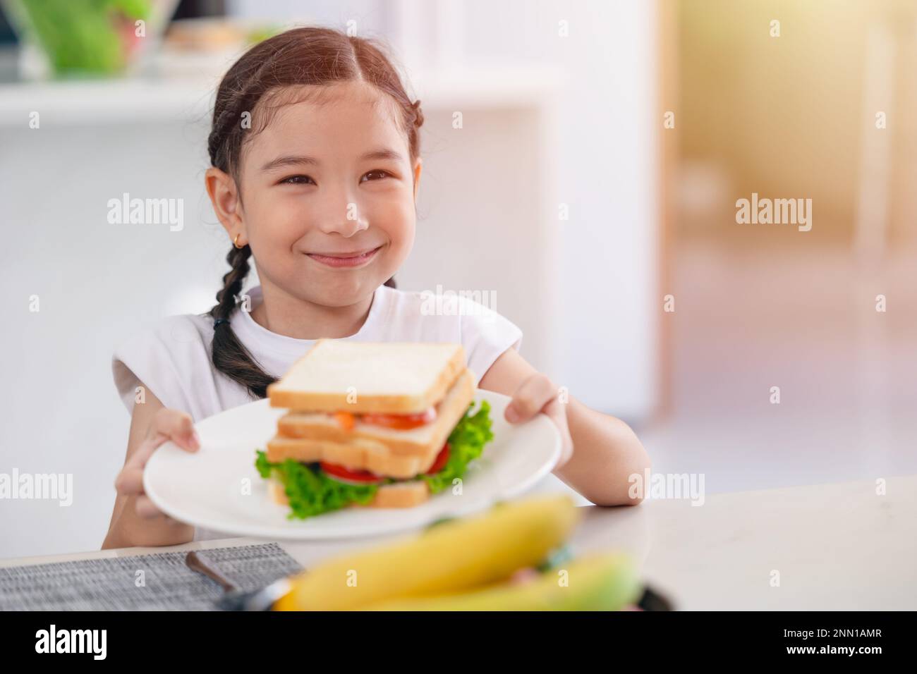 Asian cute figlia felice godere mangiare cibo sano mattina pasto insalata sandwich di verdure Foto Stock