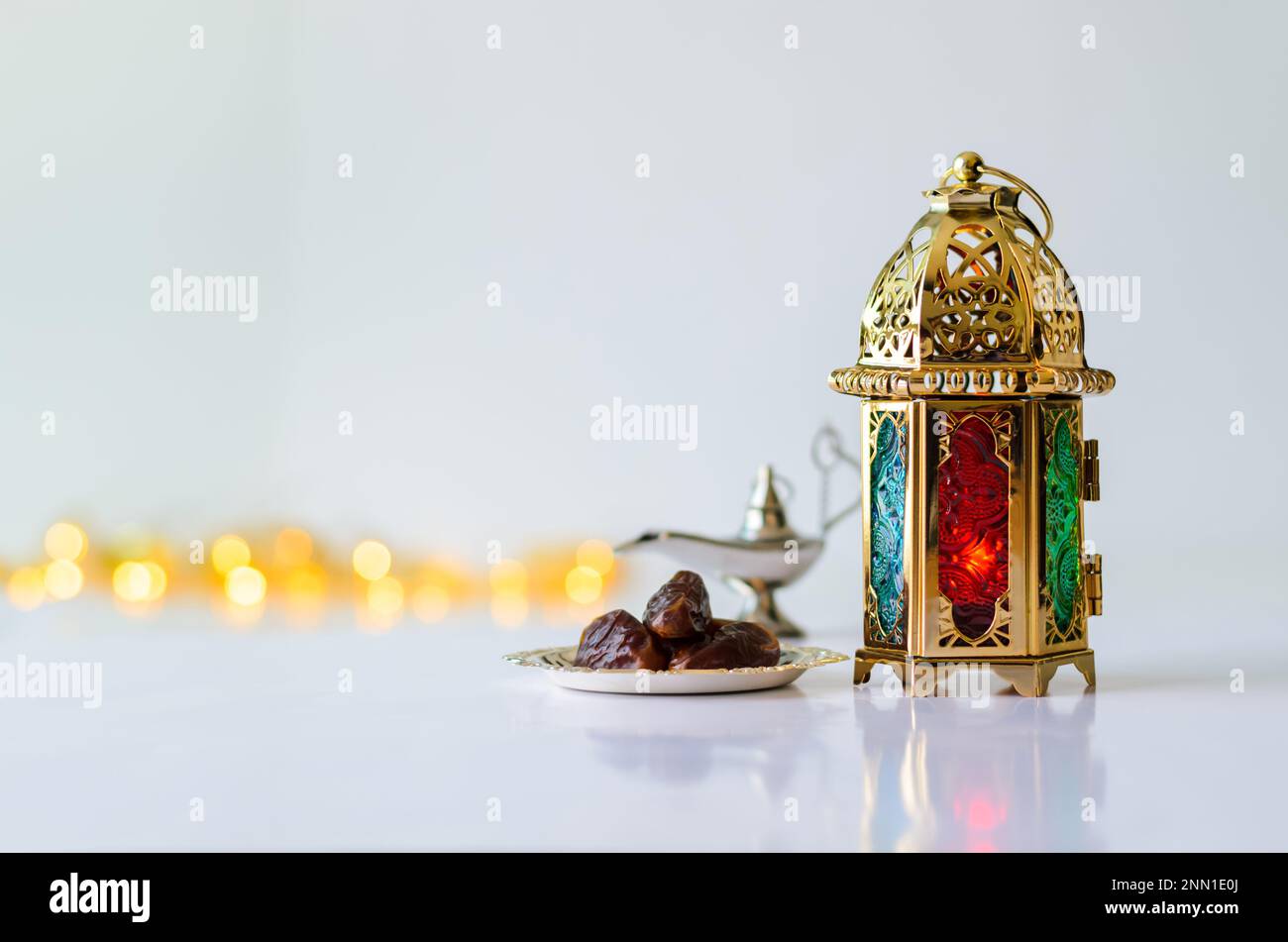 Lanterna d'oro con datteri di frutta su sfondo bianco con luci per la festa musulmana del mese santo di Ramadan Kareem. Foto Stock