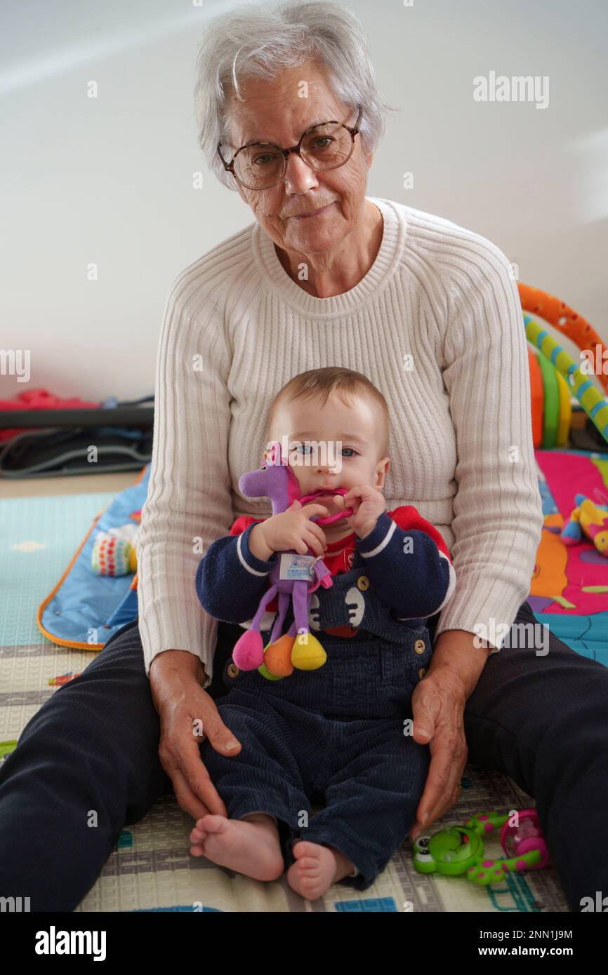 Ritratto bambino seduto sul pavimento a giocare con la nonna a casa Foto Stock