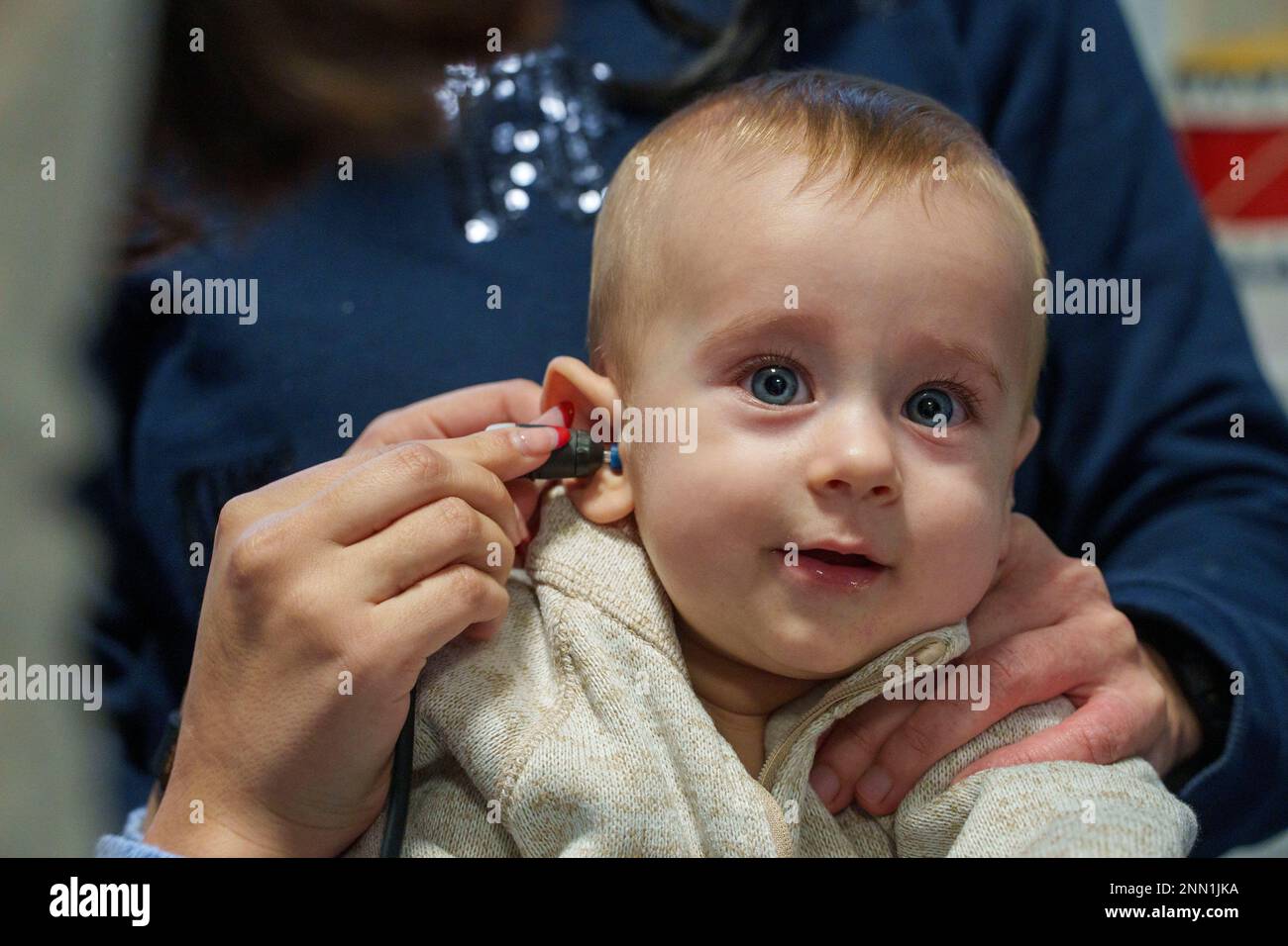 Il bambino viene sottoposto a screening per la perdita uditiva mediante test di emissione otoacustica Foto Stock