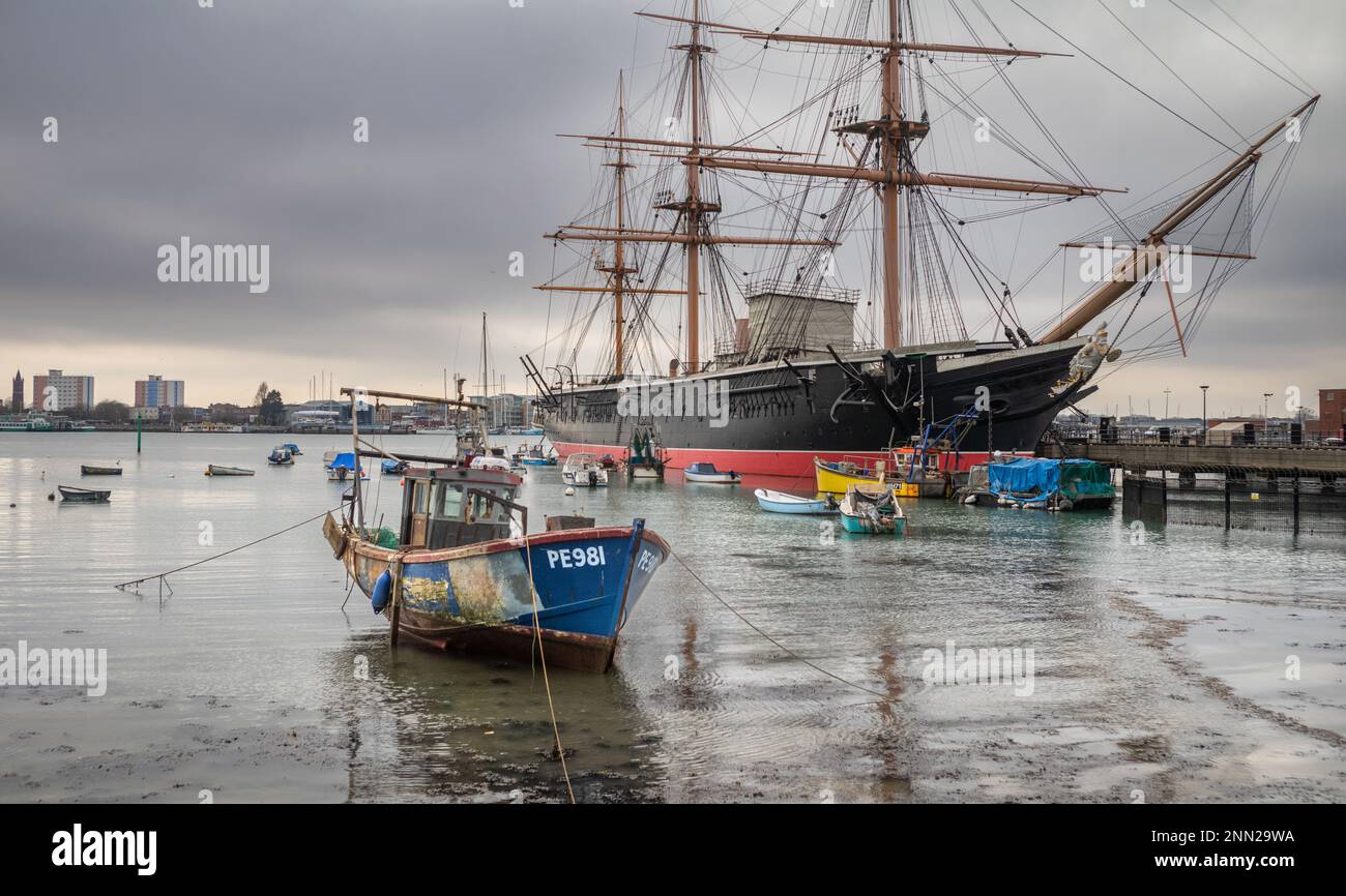 Una piccola barca da pesca chiamata Mizpah III ormeggiata nel porto di Portsmouth di fronte alla famosa nave da guerra HMS Warrior, la prima nave navale in ferro nella w Foto Stock