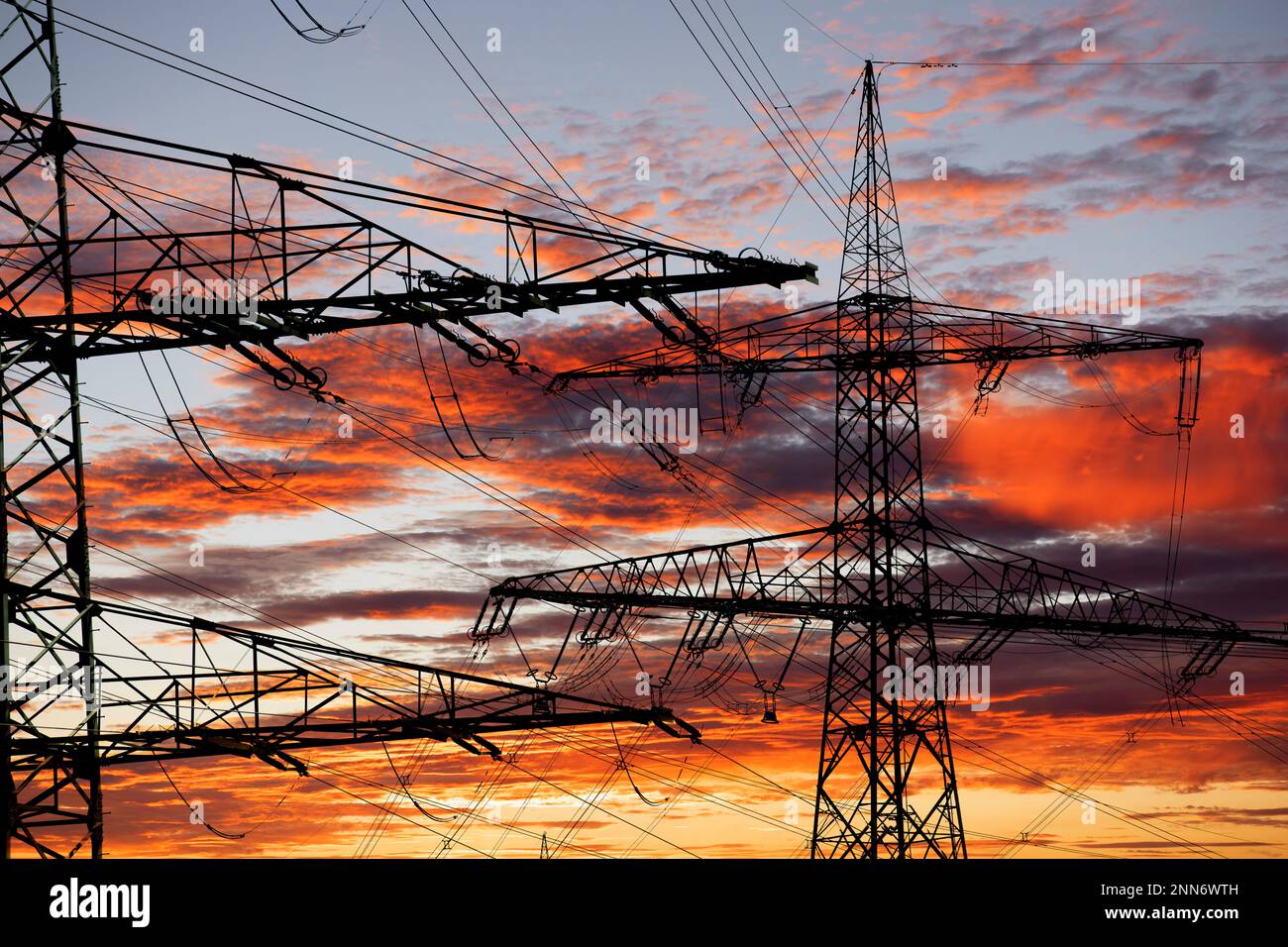 piloni ad alta tensione per l'elettricità e l'energia contro il cielo con nuvole drammatiche Foto Stock