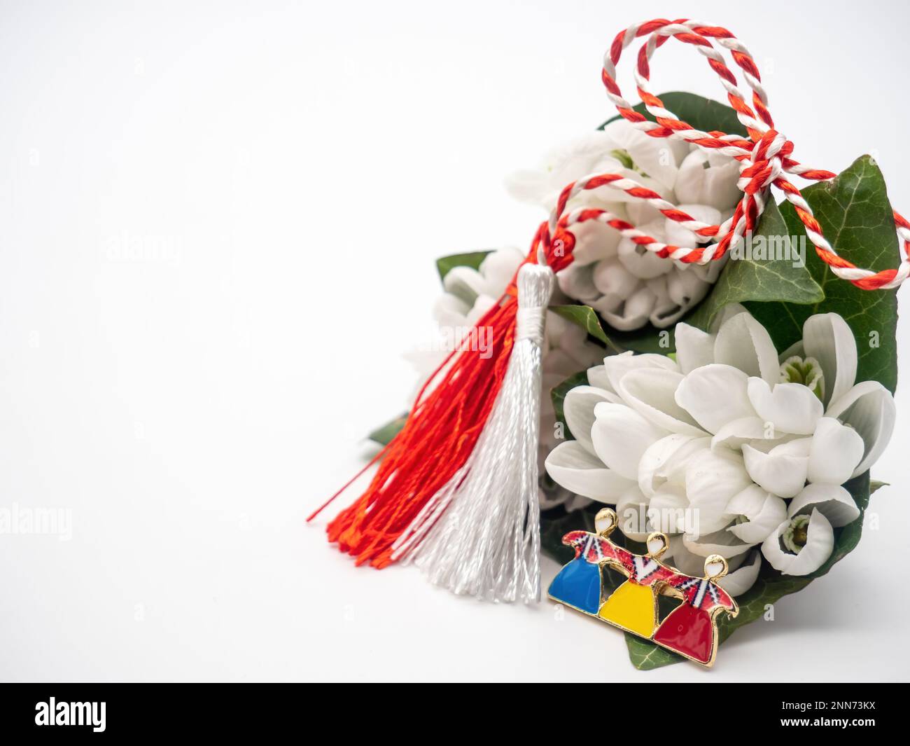 Bouquet di gocce di neve e corde bianche rosse e spilla tricolore su sfondo bianco, 1st marzo festa, Martisor Foto Stock