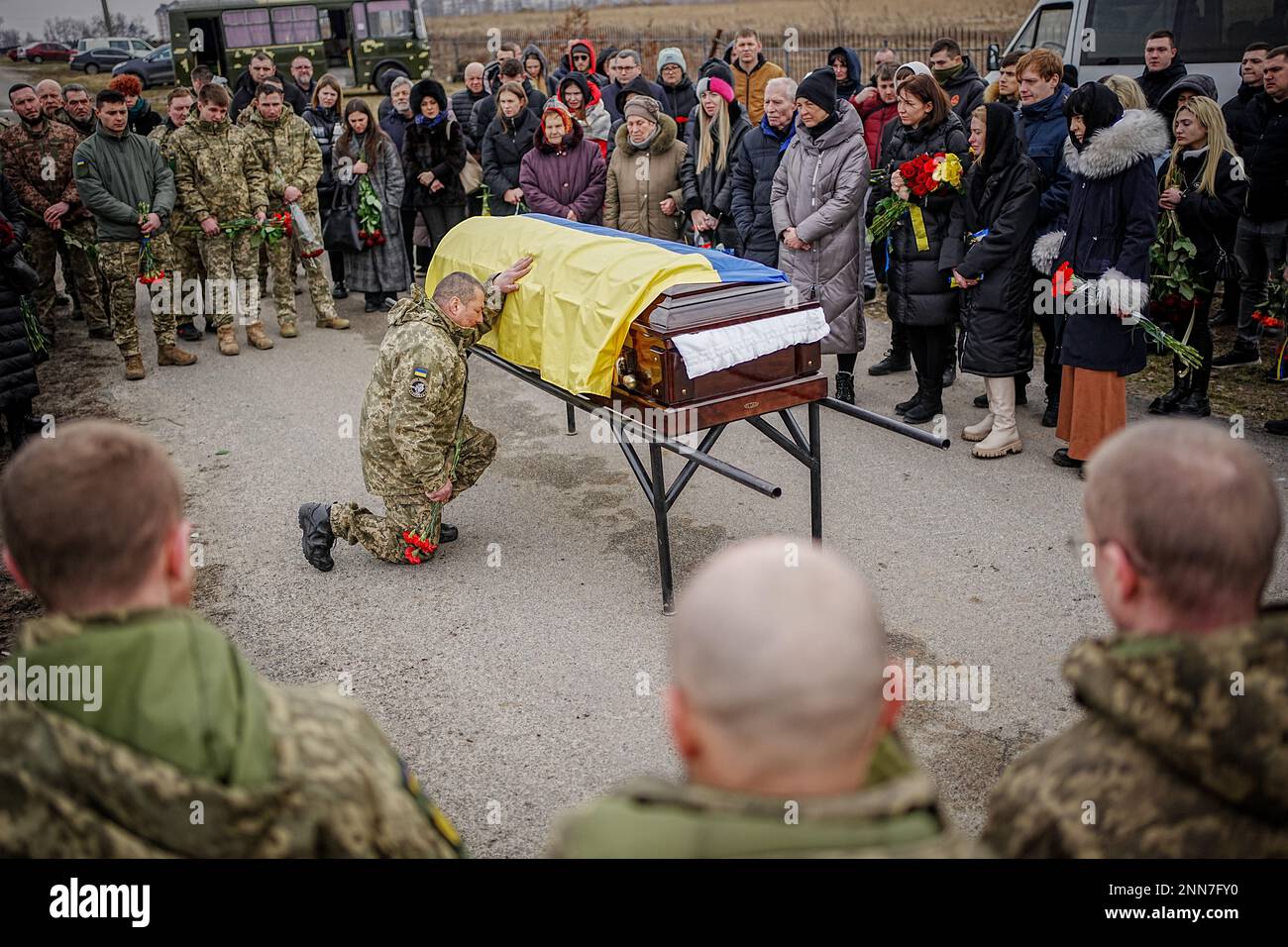 Butscha, Ucraina. 25th Feb, 2023. I compagni si inginocchiano per il soldato caduto Ihor Dyukarev al cimitero di Butsha. Il 24-anno-vecchio è stato ucciso da un guscio di serbatoio nell'est. Credit: Kay Nietfeld/dpa/Alamy Live News Foto Stock