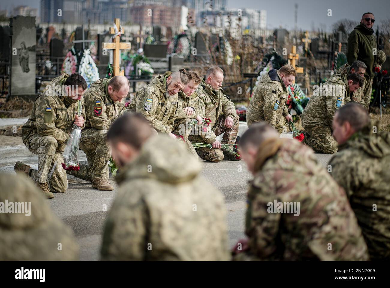 Butscha, Ucraina. 25th Feb, 2023. I compagni si inginocchiano per il soldato caduto Ihor Dyukarev al cimitero di Butsha. Il 24-anno-vecchio è stato ucciso da un guscio di serbatoio nell'est. Credit: Kay Nietfeld/dpa/Alamy Live News Foto Stock