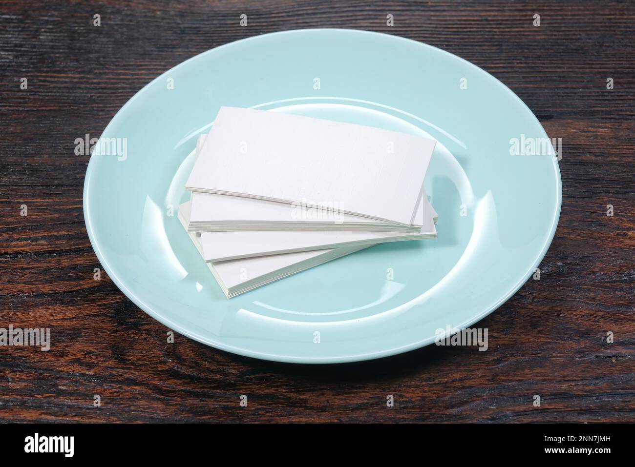 Biglietti da visita bianchi mock-up, piatto blu in porcellana su un tavolo scuro Foto Stock