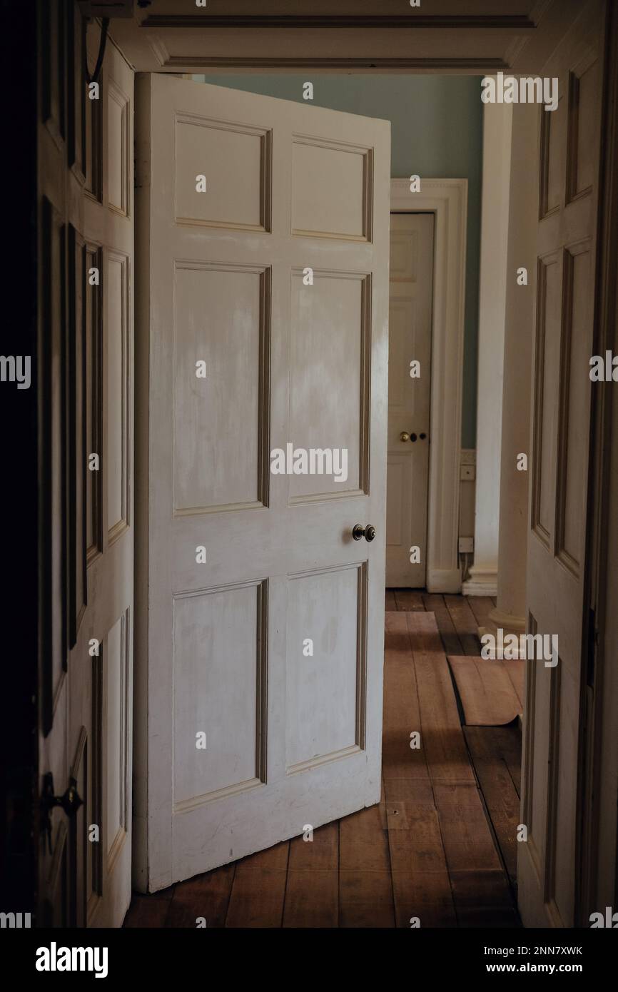 Interno di una casa georgiana a Londra, Inghilterra. Una porta conduce in un corridoio di una casa elegante con una bella luce che cade sul pannello di lavoro. Foto Stock