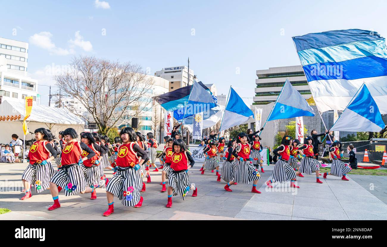 Squadra giapponese di danzatrici Yosakoi bambina che ballano e tengono naruko, clapper, nella piazza della città in occasione dell'annuale festival Kyusyu Gassai a Kumamoto. Foto Stock