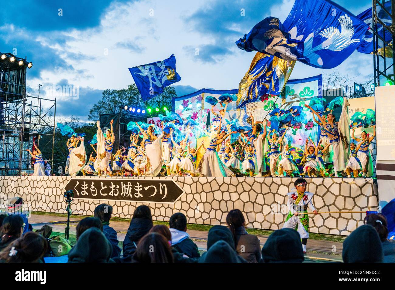 Vista del pubblico a spalla delle ballerine giapponesi Yosakoi che ballano in serata sul palco all'aperto al festival Kyusyu Gassai di Kumamoto. Foto Stock