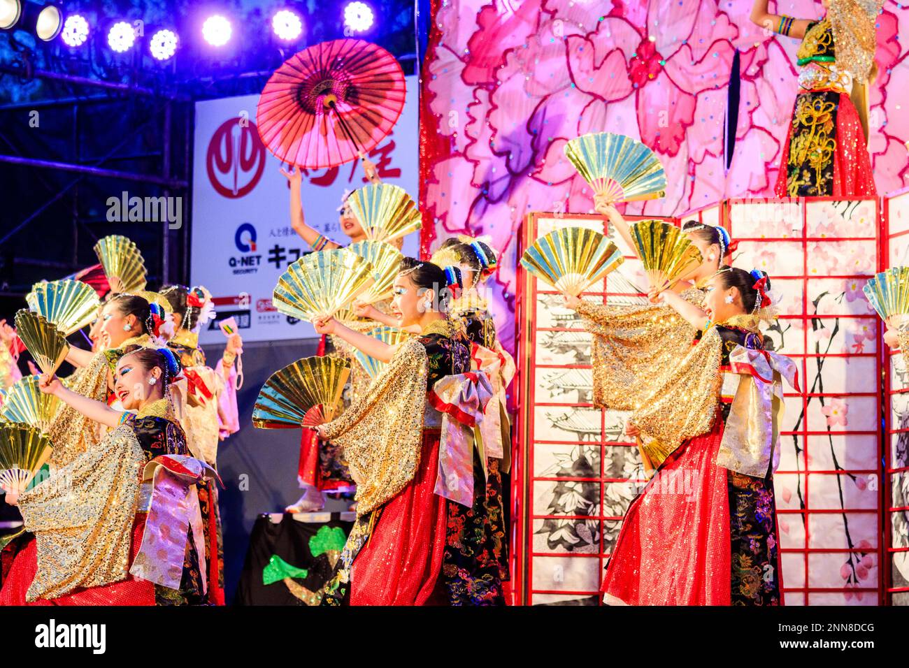 Squadra giapponese di giovani ballerine Yosakoi danzanti, tenendo tifosi in serata su un palco all'aperto al festival Kyusyu Gassai a Kumamoto. Foto Stock