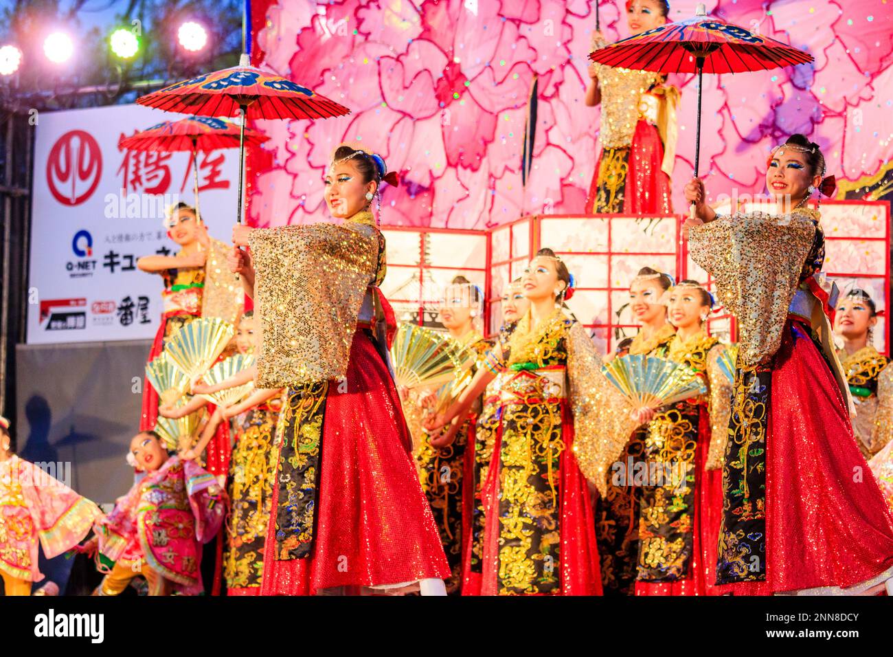 Squadra giapponese di giovani danzatrici Yosakoi, che ballano con ombrelloni la sera su un palco all'aperto al festival Kyusyu Gassai di Kumamoto. Foto Stock
