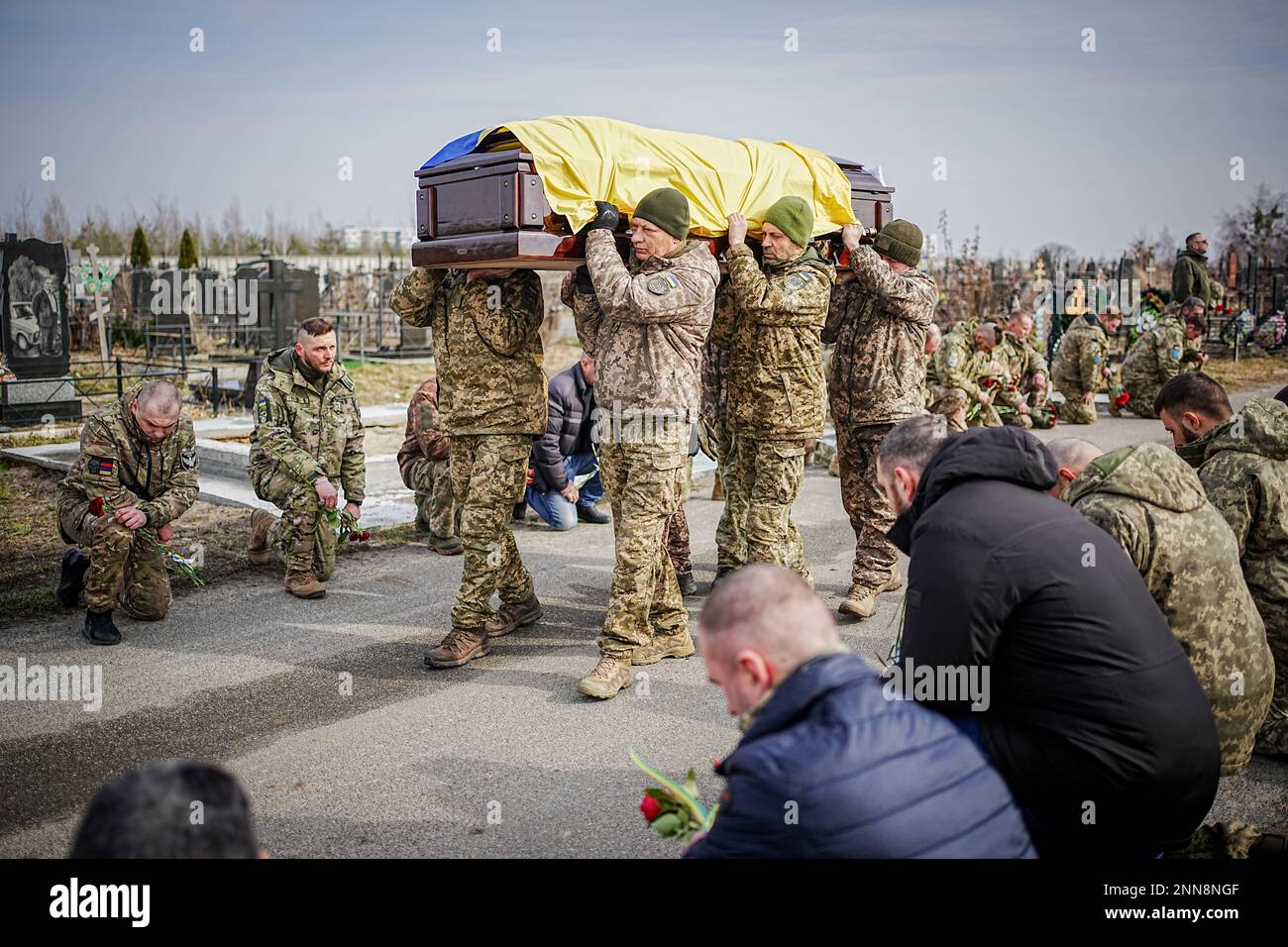 Butscha, Ucraina. 25th Feb, 2023. I compagni si inginocchiano per il soldato caduto Ihor Dyukarev al cimitero di Butsha. Il 24-anno-vecchio è stato ucciso da un guscio di serbatoio nell'est. Credit: Kay Nietfeld/dpa/Alamy Live News Foto Stock