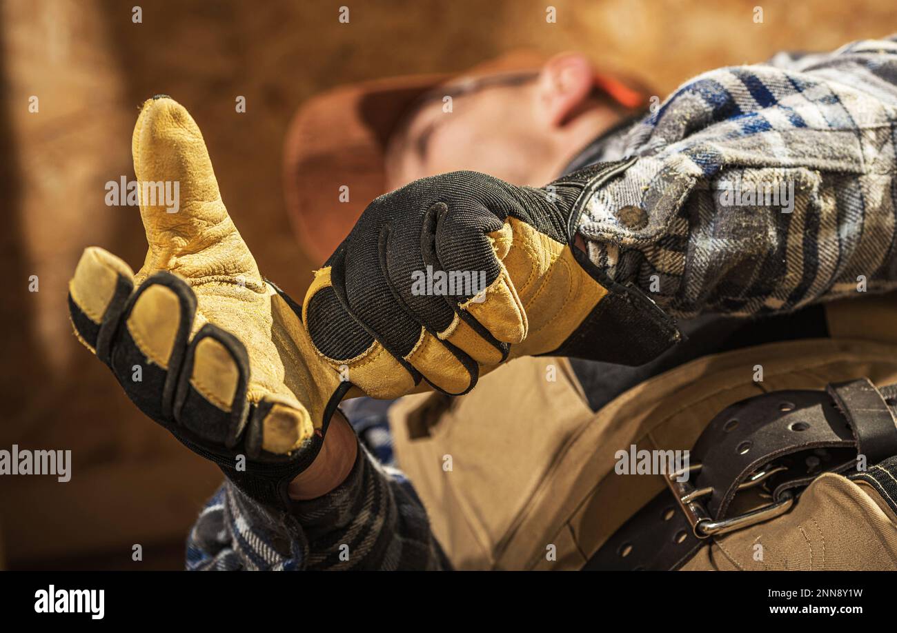 Primo piano di un professionista che lavora nel settore edile indossando guanti industriali prima di iniziare i lavori in cantiere. Foto Stock