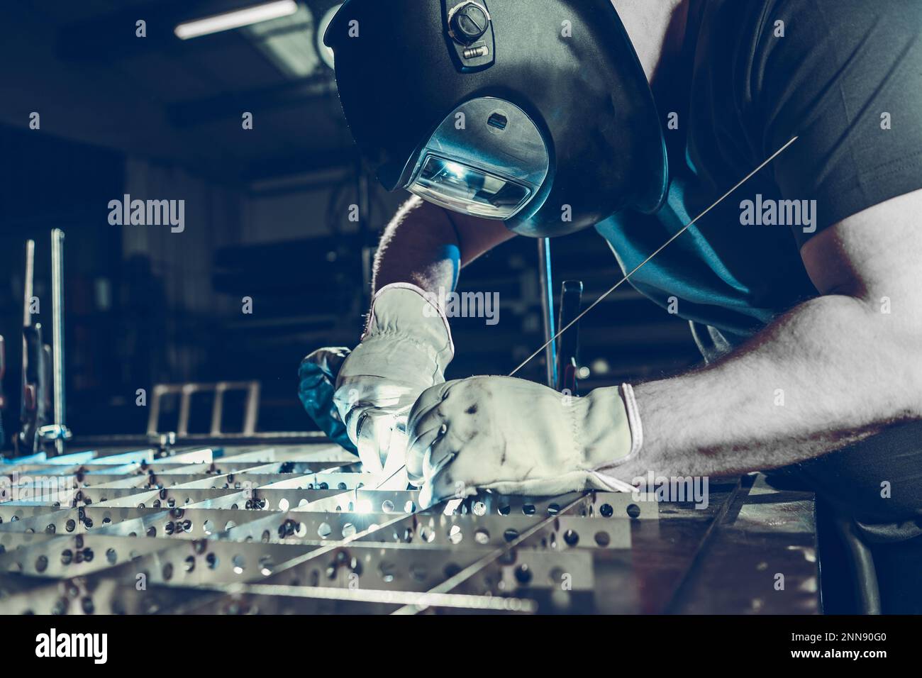Saldatore caucasico professionale nel casco protettivo durante il processo di saldatura TIG. Tema dell'industria metallurgica. Foto Stock