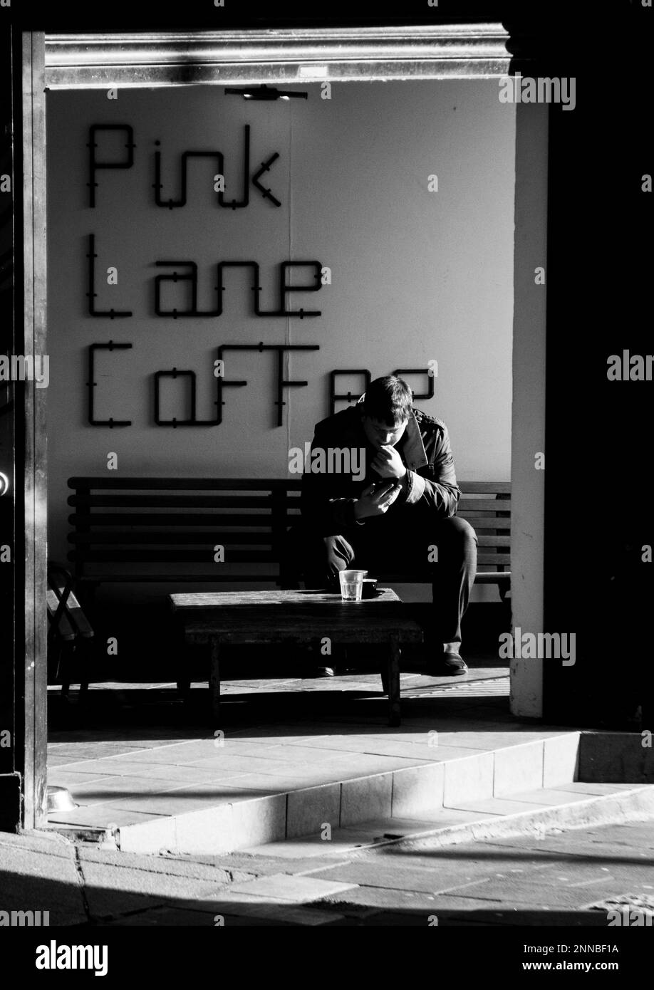 Bar, un uomo seduto al sole e sorseggiando un caffè sulla Pink Lane di Newcastle upon Tyne Foto Stock