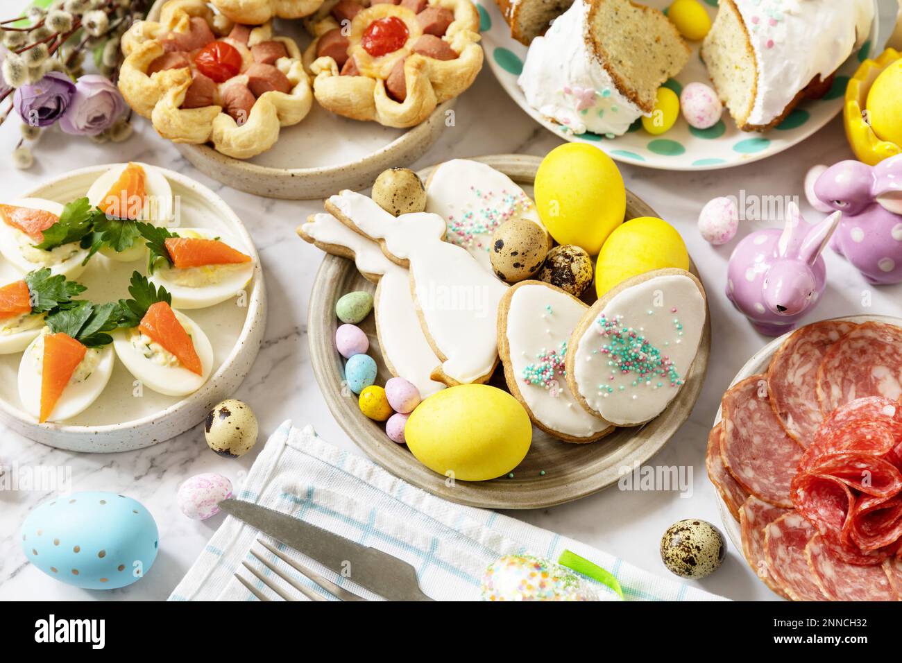 Cena festiva, brunch di Pasqua. Scena di Pasqua con un assortimento di cottura, dessert, uova farcite e uova tinte su uno sfondo di marmo. Foto Stock