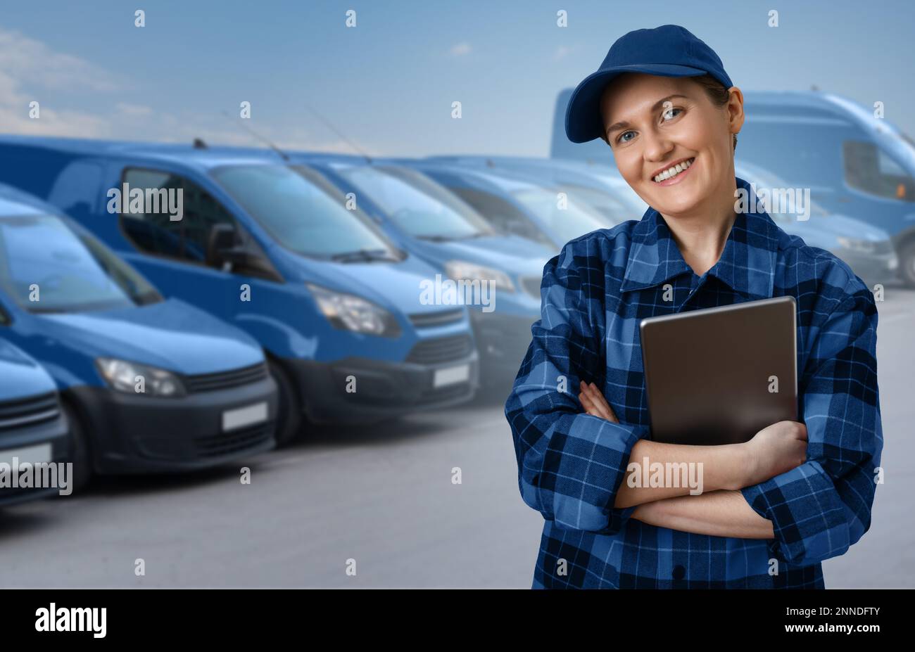 Manager con un tablet digitale sullo sfondo di furgoni. Gestione della flotta Foto Stock