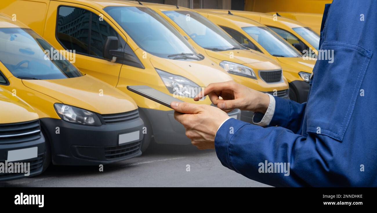Manager con un tablet digitale sullo sfondo di furgoni. Gestione della flotta Foto Stock