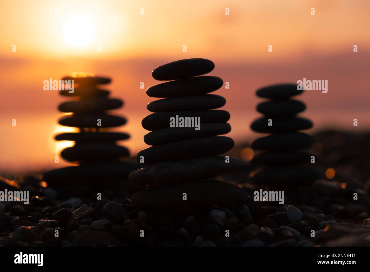 Profilo equilibrato piramidale di ciottoli sulla spiaggia al tramonto con Mare sullo sfondo. Pietre Zen sulla spiaggia di mare, meditazione, spa, armonia, calma, Foto Stock