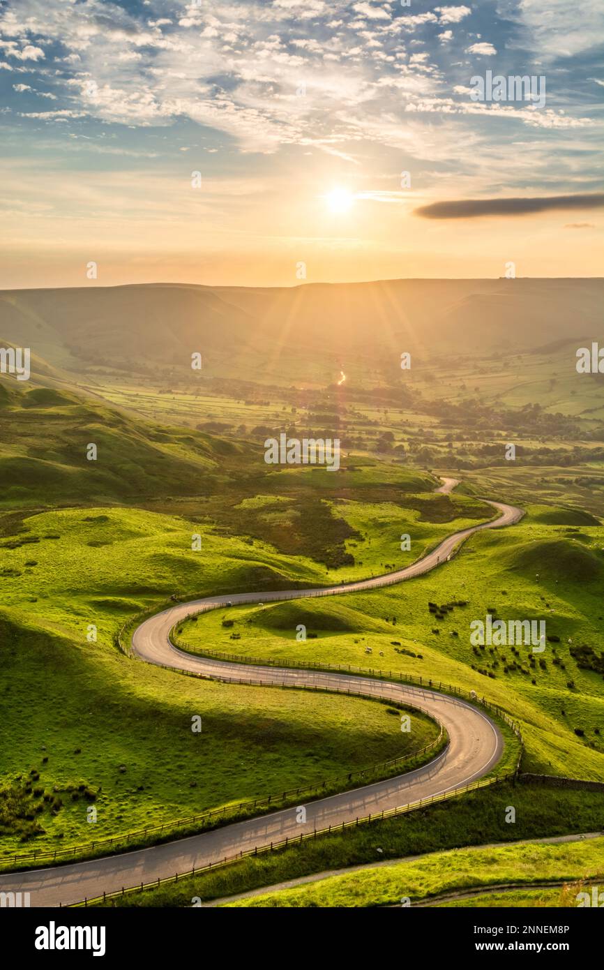 Tortuosa strada di campagna che conduce a Edale nel Peak District Inglese con una bella luce dorata che splende attraverso la valle. Foto Stock