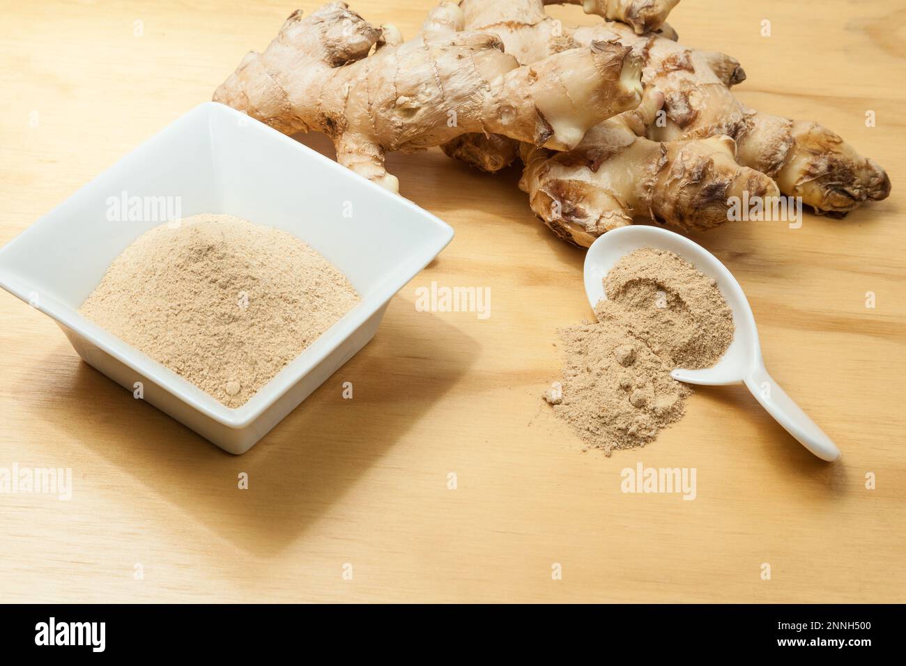 Radici fresche e polvere di zenzero - Zingiber officinale; foto su sfondo ligneo. Foto Stock