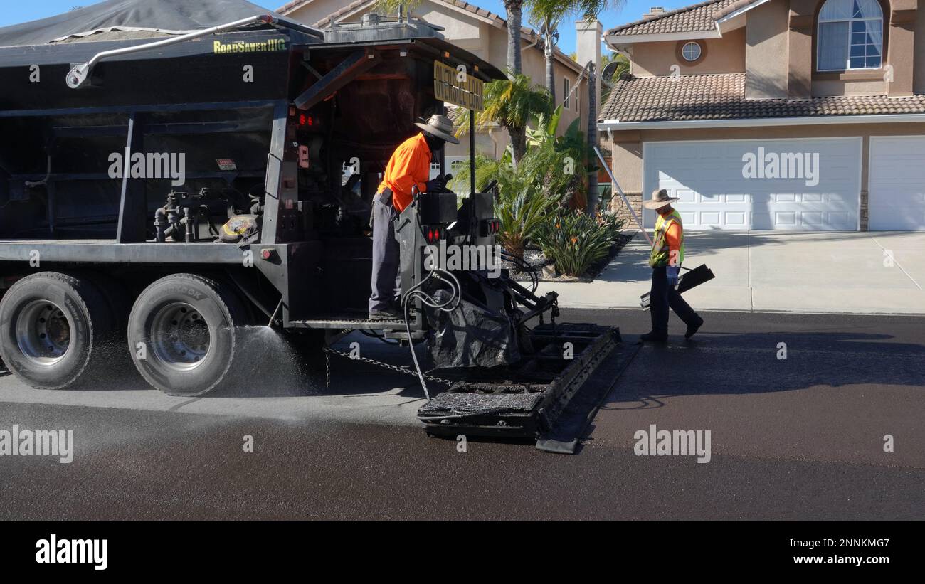 Vista, CA USA - Febbraio 6 2023: Un equipaggio di lavoratori applica la foca di liquame a una strada residenziale Foto Stock