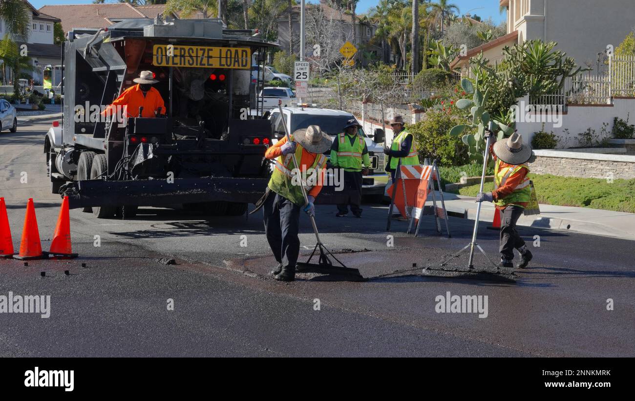 Vista, CA USA - Febbraio 6 2023: Un equipaggio di lavoratori applica la foca di liquame a una strada residenziale Foto Stock