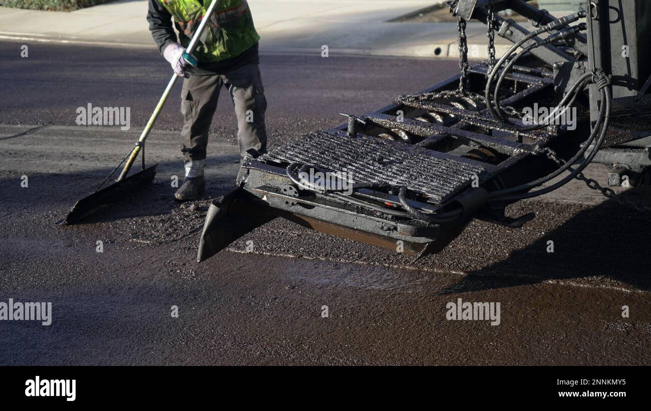 L'operatore che indossa stivali e indumenti protettivi leviga la guarnizione in slurry fresco Foto Stock