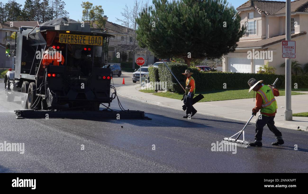 Vista, CA USA - Febbraio 6 2023: Un equipaggio di lavoratori applica la foca di liquame a una strada residenziale Foto Stock