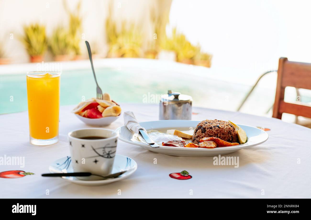 Primo piano di una colazione tradizionale su un tavolo con una piscina sullo sfondo. Colazione al mattino sul tavolo vicino alla piscina Foto Stock