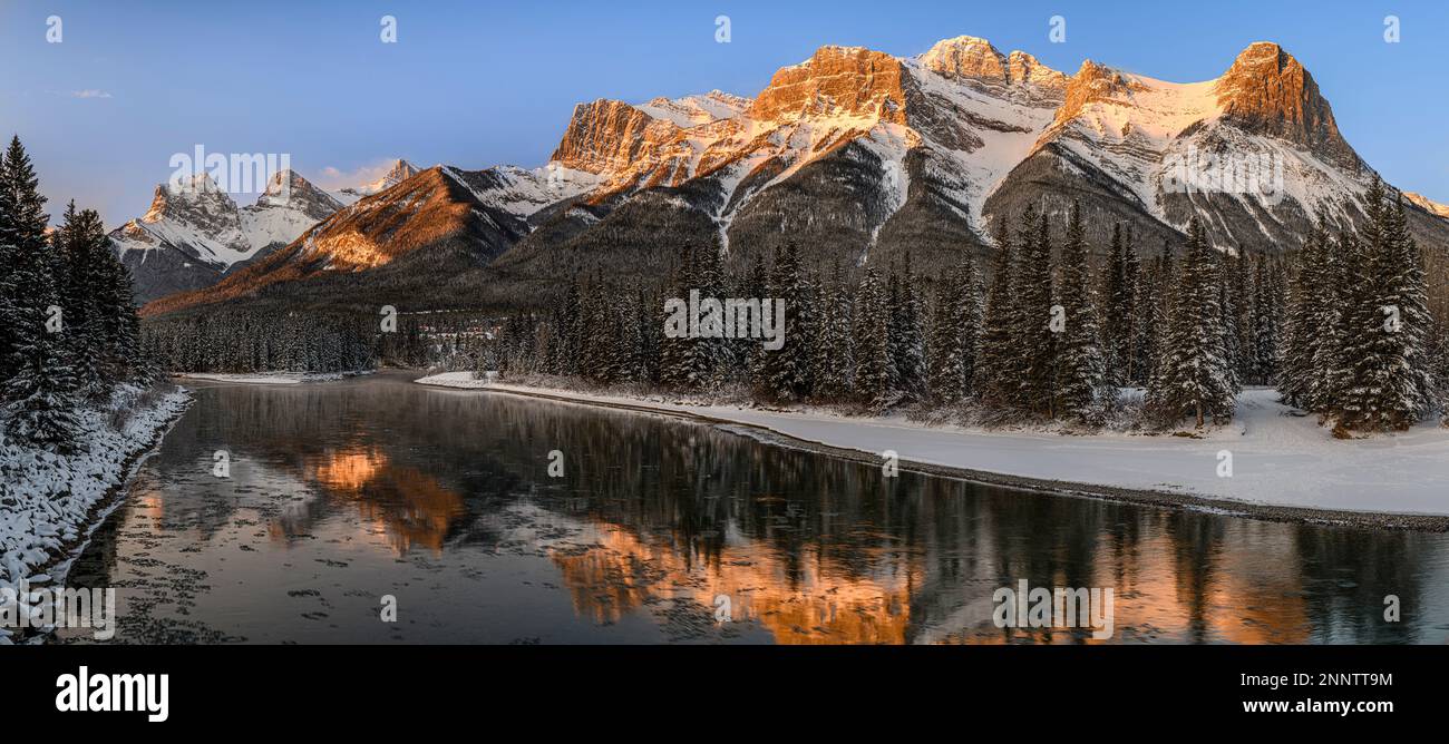 Bow River scorre attraverso il paesaggio innevato di montagna, Canmore, Alberta, Canada Foto Stock