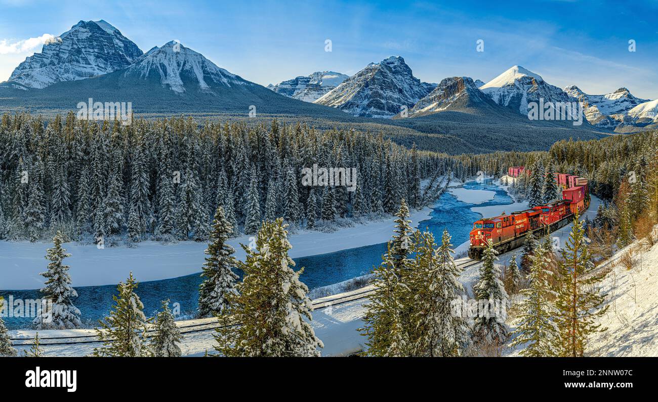 Treno che si muove lungo Morant's Curve e Bow River con catena montuosa sullo sfondo, Lake Louise, Alberta, Canada Foto Stock