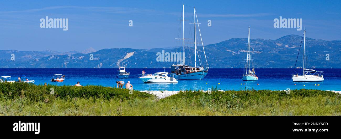 Turisti in spiaggia e barche a vela a Lakka Bay, Paxos, Isole IONIE, Grecia Foto Stock