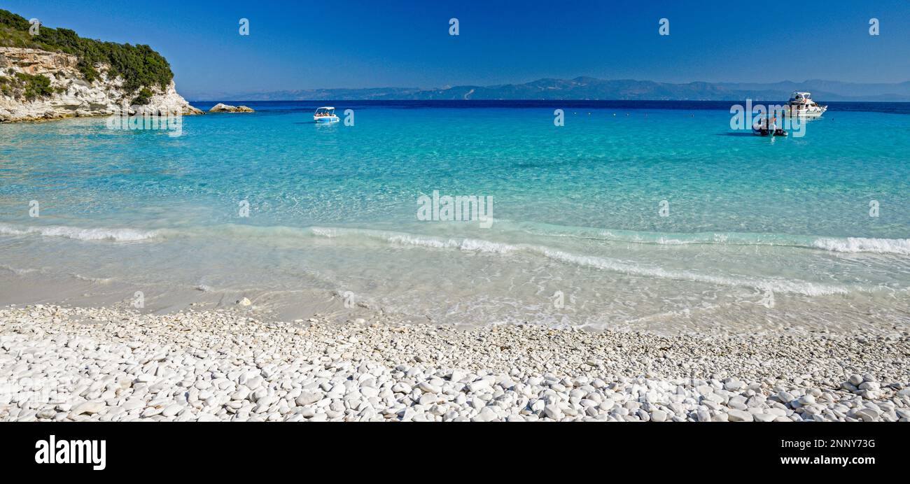 Spiaggia con ciottoli e barche in mare, Paxos, Isole IONIE, Grecia Foto Stock