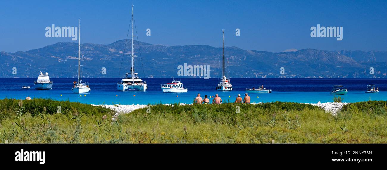 Turisti in spiaggia e barche a vela a Lakka Bay, Paxos, Isole IONIE, Grecia Foto Stock